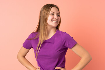 Fototapeta premium Teenager Ukrainian girl isolated on pink background posing with arms at hip and smiling