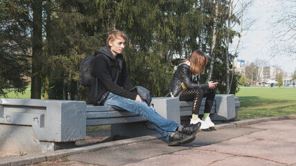 A young guy and a girl are sitting on a bench