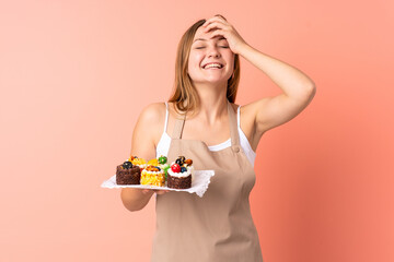 Pastry Ukrainian chef holding a muffins isolated on pink background laughing