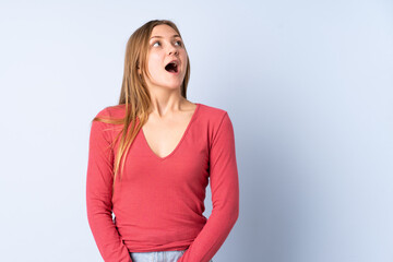 Teenager Ukrainian girl isolated on blue background looking up and with surprised expression