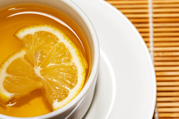 Fresh honey mixed with fresh lemon juice  and hot water in white cup for drink .Lemon slices in a cup