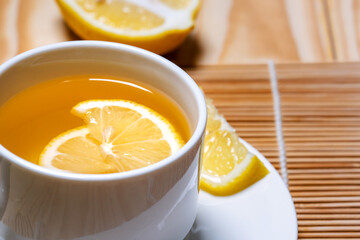 Fresh honey mixed with fresh lemon juice  and hot water in white cup for drink .Lemon slices in a cup and plate