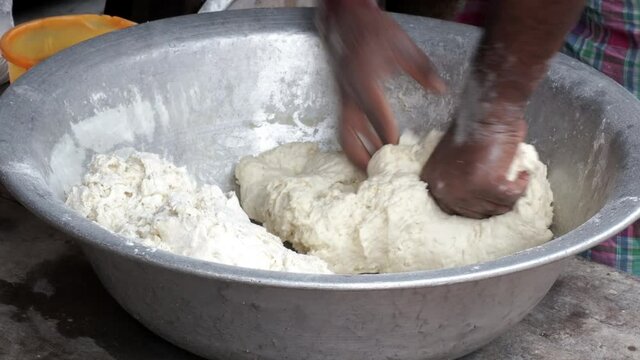 The dough in the hand of the chef on a dark black wood background. Baking bread, pizza, pasta. A recipe from the chef for pizza, bread or pastries. Ho