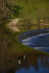 a horse shoe shaped weir the welsh countryside with reflective green waters surrounding it 