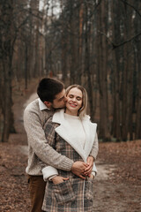 A young, loving couple have fun walking in nature in the rain.