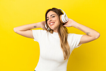 Fototapeta na wymiar Caucasian woman isolated on yellow background listening music