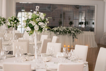 Centerpiece made of green leaves and fresh flowers stands on the dinner table. Wedding day. Fresh flowers decorations.