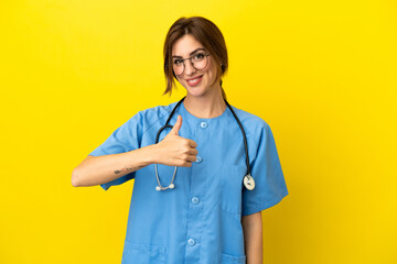 Surgeon doctor woman isolated on yellow background giving a thumbs up gesture