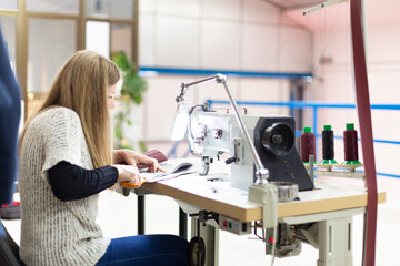 Caucasian woman working in a sewing workshop. Selective focus. Space for text.