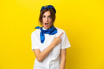 Airplane stewardess woman isolated on yellow background surprised and pointing side