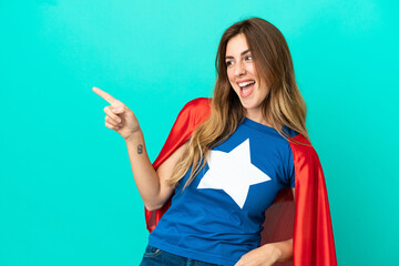 Super Hero caucasian woman isolated on blue background pointing finger to the side and presenting a product © luismolinero