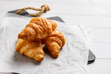 Board with tasty croissants on dark wooden table, closeup.