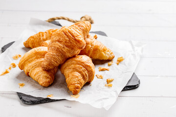 Board with tasty croissants on dark wooden table, closeup.