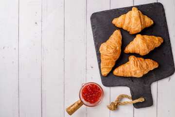 freshly baked croissants on white wooden table, top view