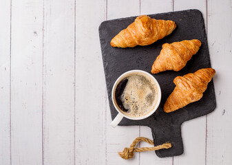 Coffee white cup, croissants on white wooden table background, selective focus. Breakfast concept