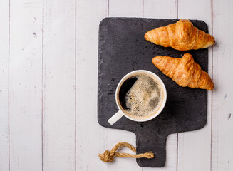 Coffee white cup, croissants on white wooden table background, selective focus. Breakfast concept