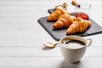 Coffee white cup, croissants on white wooden table background, selective focus. Breakfast concept