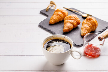 Coffee white cup, croissants on white wooden table background, selective focus. Breakfast concept