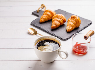 Coffee white cup, croissants on white wooden table background, selective focus. Breakfast concept