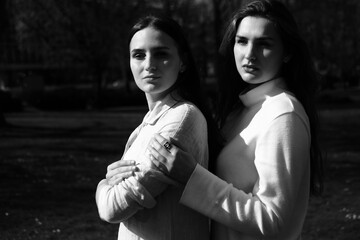 Black and white portrait of two girls. Friends in white dresses walking in the park