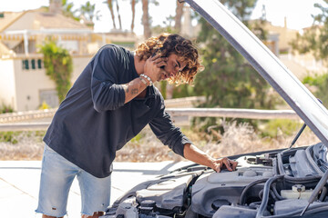 Fototapeta na wymiar Young caucasian man trying to repair a breakdown in his car