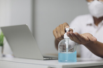Obraz premium A men is pressing alcohol gel, hand sanitizer gel to clean hands, focus at the hand, working at home, the corona virus crisis event, covid19