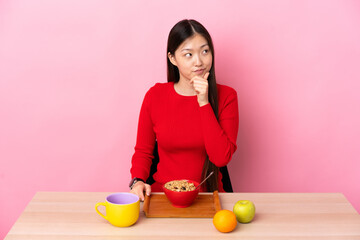 Young Chinese girl  having breakfast in a table thinking an idea while looking up