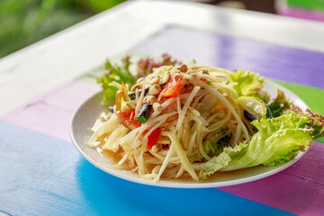 Spicy papaya salad or call Som-tam Thai in white plate on wooden table