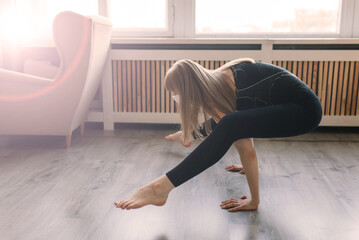 Meditating woman wearing a medical face mask to protect from corona virus, yoga position on mat home