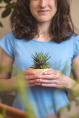 A woman holds a pot of succulent in her hands
