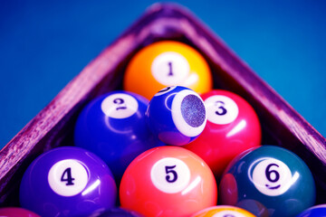 Sports game of billiards on a green cloth. Multi-colored billiard balls in a wooden triangle with...