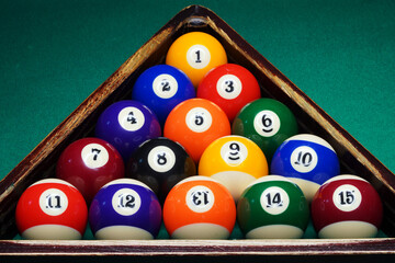 Sports game of billiards on a green cloth. Multi-colored billiard balls in a wooden triangle with...