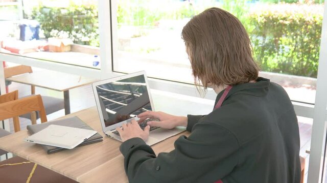 businessman typing on keyboard. Tablet and notebook next to laptop on the table in modern office.