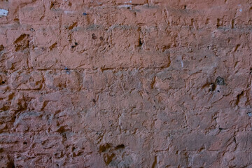 A wall of old brown bricks covered with semi-peeled paint. Copy space