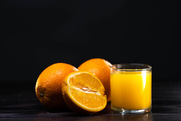Glass of orange juice from above on wood table. Slice oranges near the glass