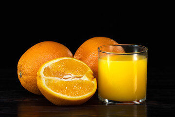 glass of fresh orange juice and oranges on a vintage wooden background