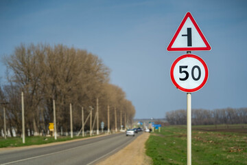 Road signs speed limit 50 km per hour. The road turns left