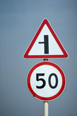 Road signs speed limit 70 km per hour. The road turns left. Close up shot
