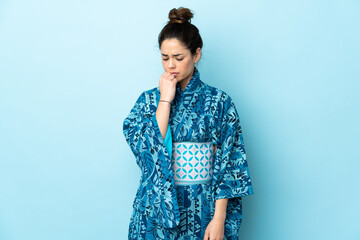 Woman wearing kimono over isolated background having doubts