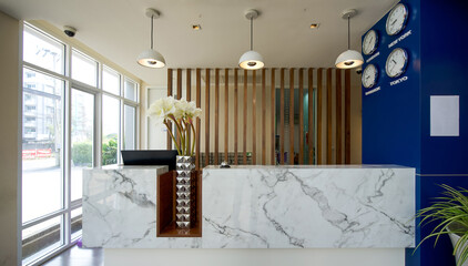 A long white marble reception counter located in the hotel lobby.