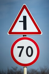 Road signs speed limit 70 km per hour. The road turns left. Close up shot raw