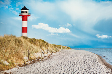 Leuchtturm am Strand einer Insel, Sylt, an der Küste hinter und auf Düne mit Strandsand und...
