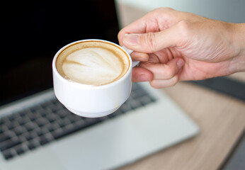 A cup of latte art coffee in hand.