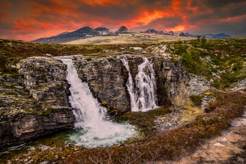 beautiful waterfalls with crystal clear water with mountains in the background at sunset Norway.