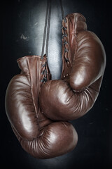 Brown leather boxing gloves lie on a black punching bag. Sport equipment. Training. The fight....