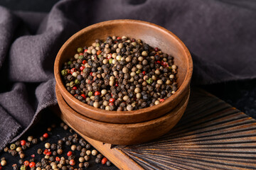 Bowl with peppercorns on dark background