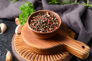 Bowl with peppercorns on dark background