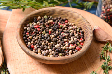 Plate with peppercorns on wooden background