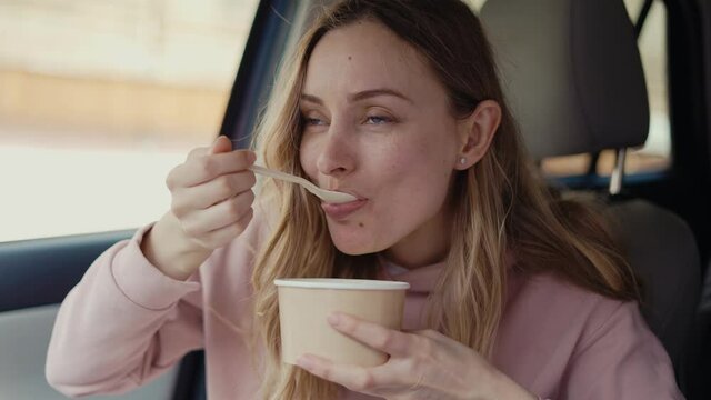 Woman having her meal inside the parked car, slow mo