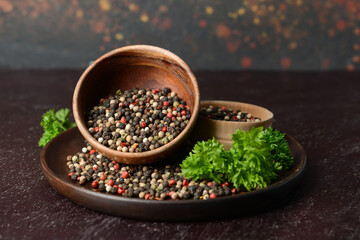 Bowls with peppercorns on dark background